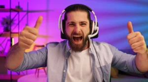Excited bearded man wearing a gaming headset giving thumbs up with colorful neon background.